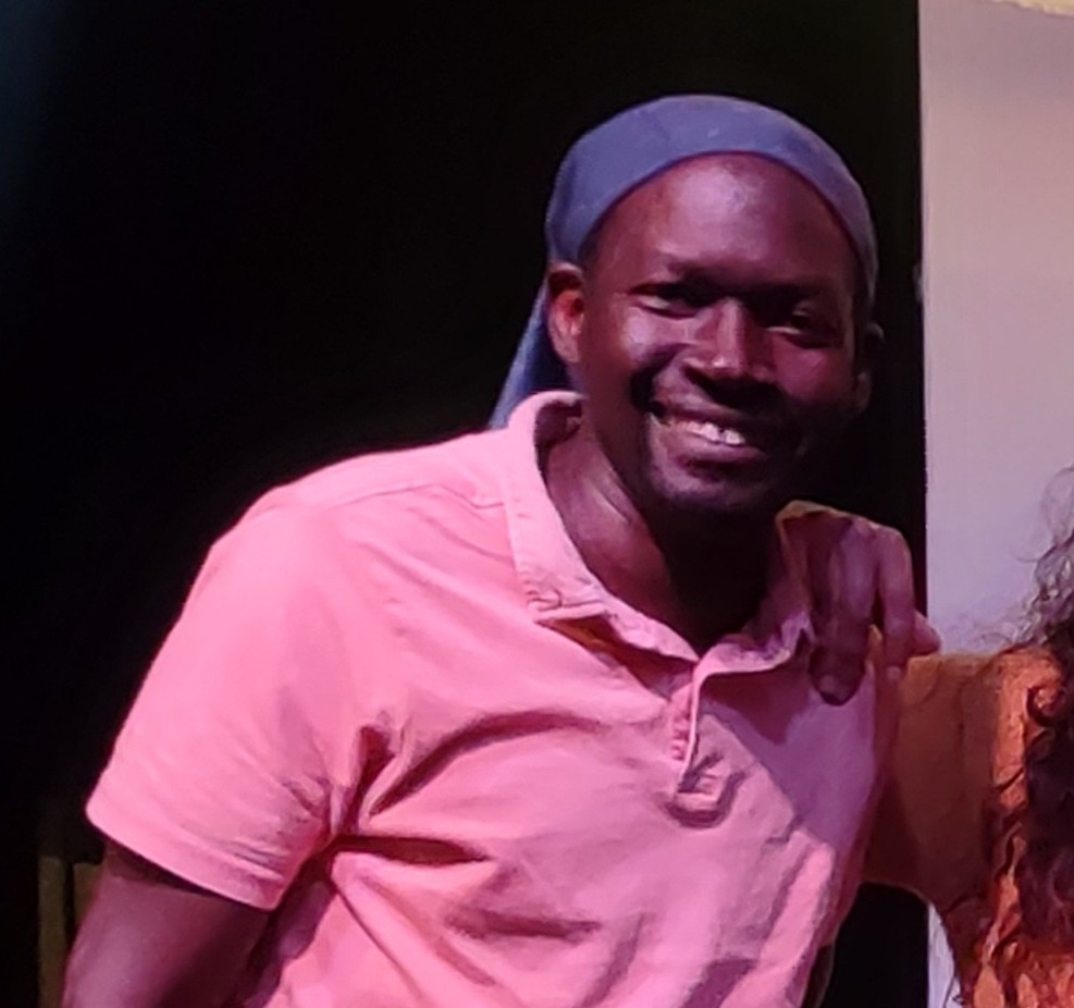 Ahmet Diop, actor, sonriendo con polo rosa y pa&ntilde;uelo en la cabeza